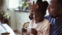 Father and daughter in front of computer for telehealth appointment